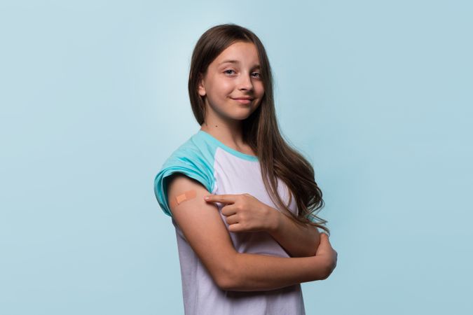 Girl pointing to bandage on arm after vaccination