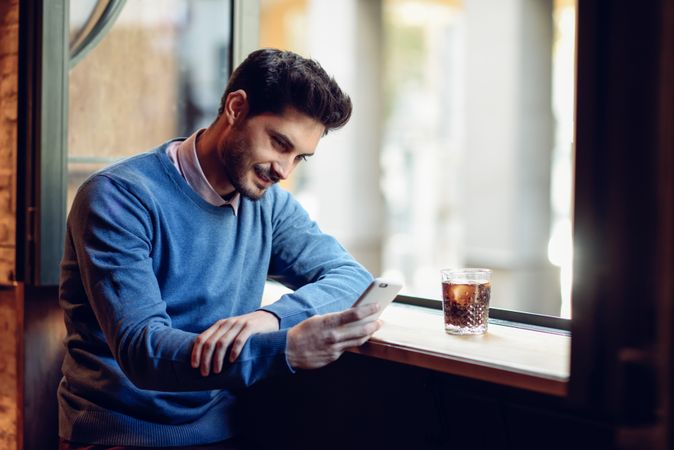 Man sitting in cafe window with cafe and smartphone