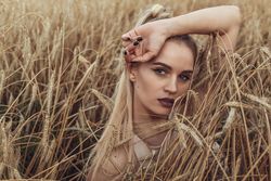 Portrait of young woman with purple lipsticks in wheat field