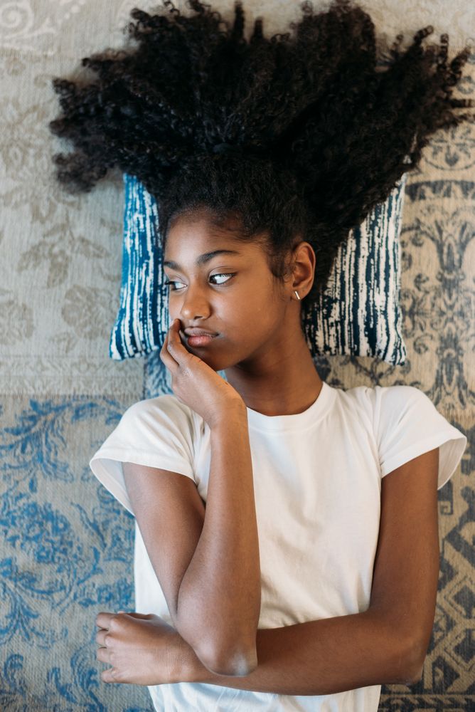 Beautiful young Black teenage girl lying down in a rug