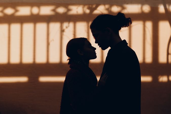 Silhouette of two people about to kiss