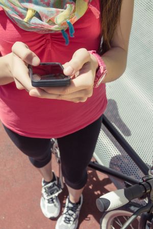 Sportive woman with fixie bike looking smartphone