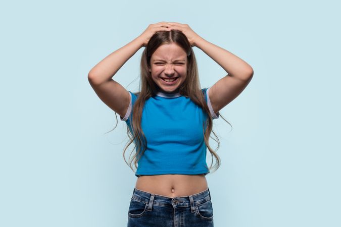 Girl holding head in frustration or pain, expressing discomfort