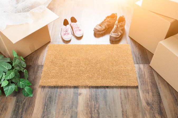 Home Sweet Home Welcome Mat, Moving Boxes, Women and Male Shoes and Plant on Hard Wood Floors