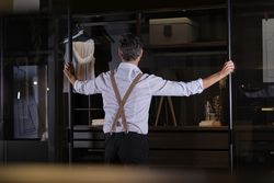Anonymous male standing near wardrobe in dark room