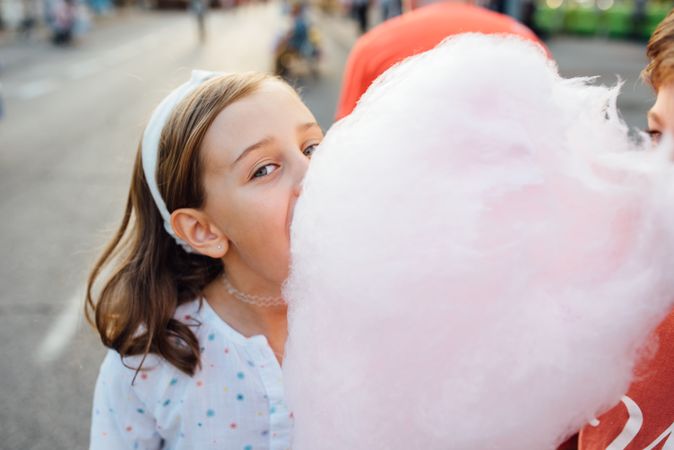 Cheerful girl eating cotton candy on street