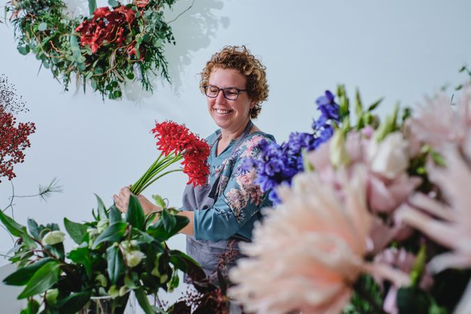 Smiling adult woman with bunch of flowers in floral store