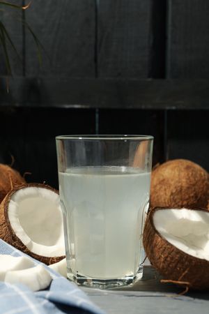 Coconut and water on wooden background, close up. Tropical fruit