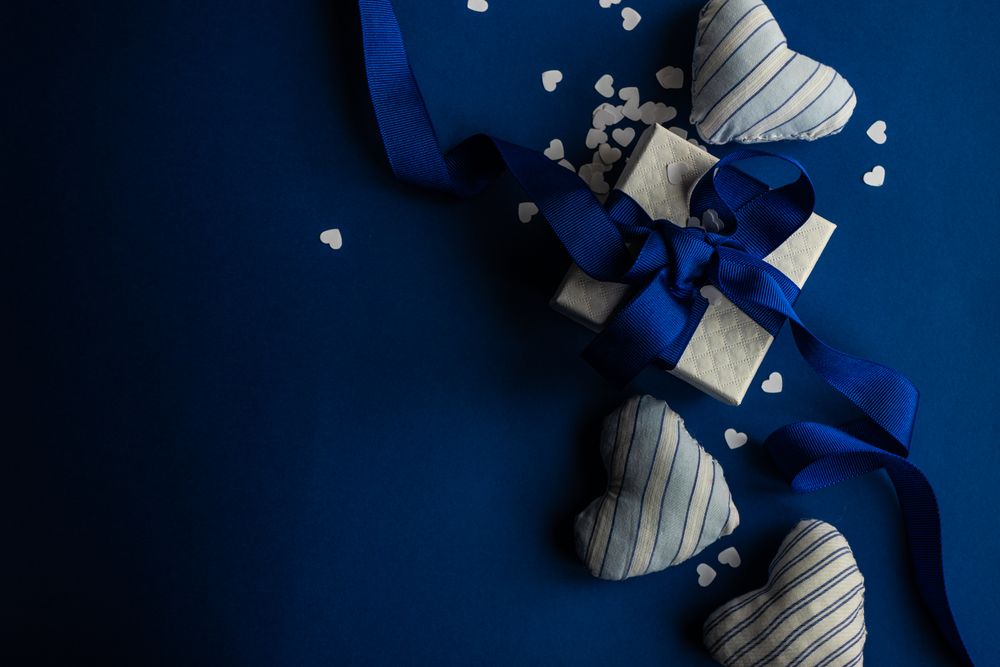 Top view of blue Valentine day concept with felt heart decoration, confetti and gift
