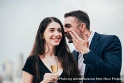 Businessman whispering to businesswoman with champagne 0WDkP5