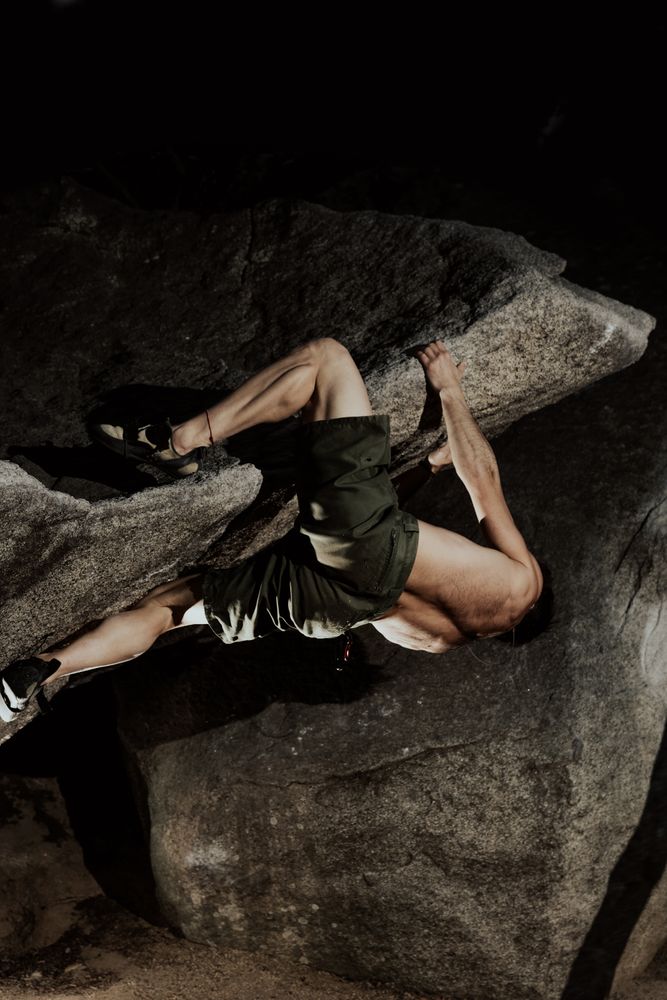 Man practicing rock climbing among large rocks in a forest