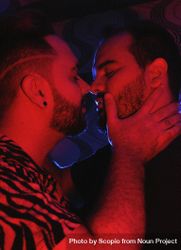 Two men kissing in red lit room 43EvP0
