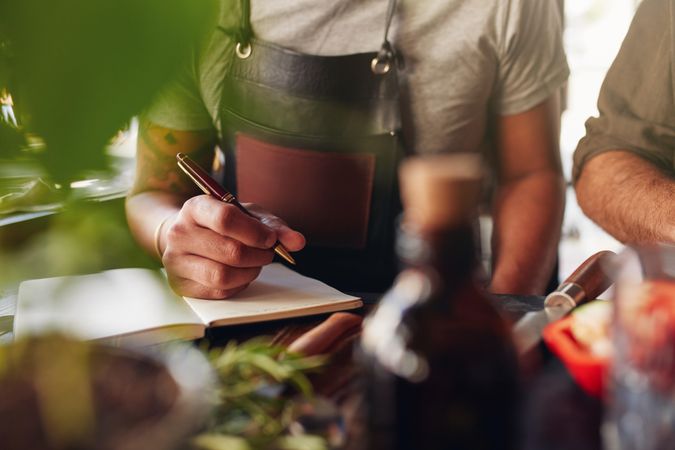 Man writing down notes while creating new cocktail recipe