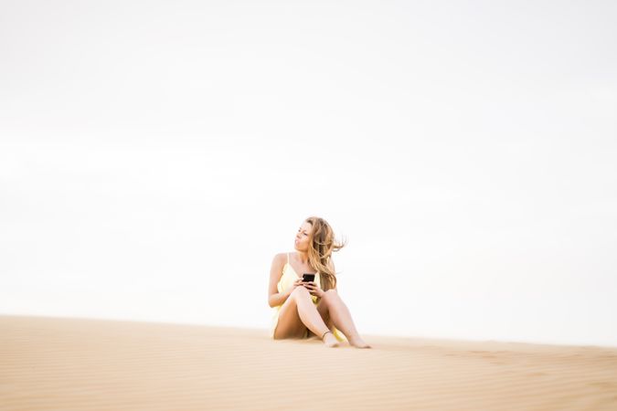 Happy woman using smartphone in desert