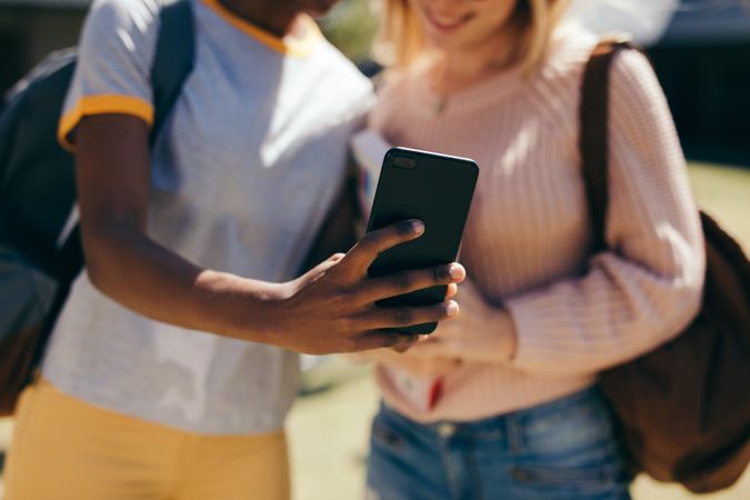 Cropped shot of two students taking selfie with cell phone