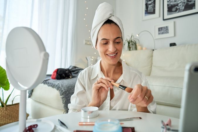 Smiling woman testing foundation on hand with brush