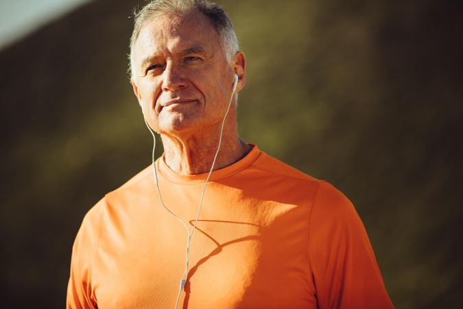 Man in fitness wear listening to music outdoors on a sunny day