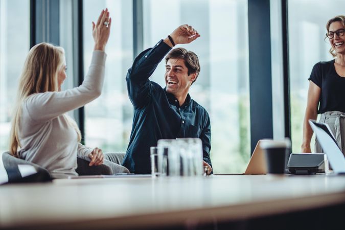 Cheerful coworkers giving high five during meeting