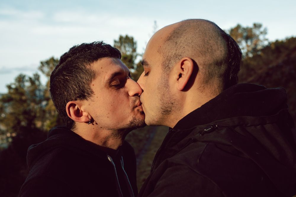 Men hugging and kissing in park