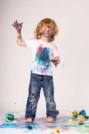 Cheerful boy covered with colorful paints