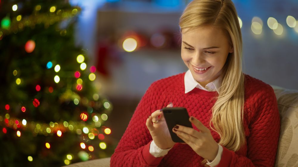Blonde Woman Sits on a Couch and Uses Smartphone.