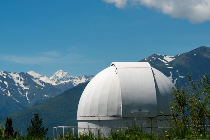 Observatory dome with snowy mountains in the background.