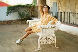 Happy romantic woman in makeup sitting on armed wicker bench outdoors