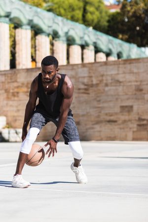 Black man playing basketball on sports ground