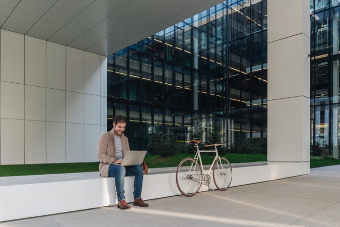 Cheerful businessman using laptop on street