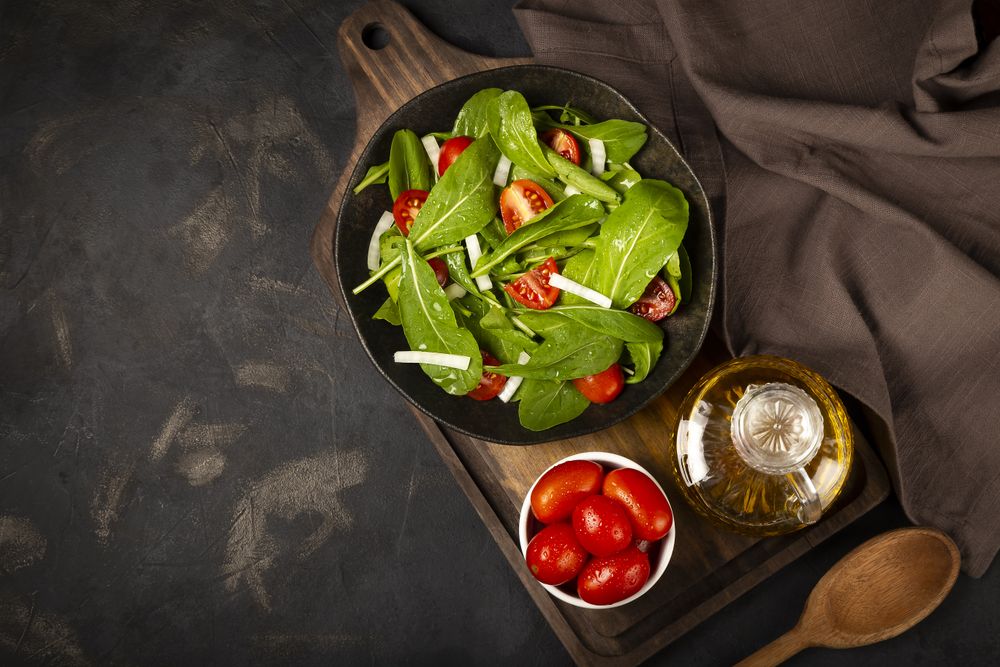 Arugula salad with tomatoes on dark background.