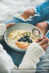 Female holding bowl of homemade oatmeal with fruits and berries 41Py85