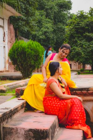 Two Indian woman in colorful saris sitting on concrete stairs outdoor