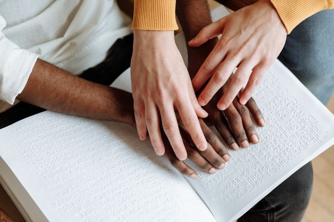 Cropped image of person teaching braille to a Black man with visual impairment