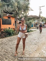 Woman wearing blue bikini top and beige skirt standing outdoor 5oOl15