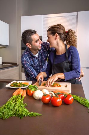 Couple joking together as they chop vegetables for meal