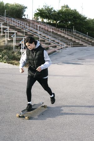 Teenage girl skating on a longboard in a park