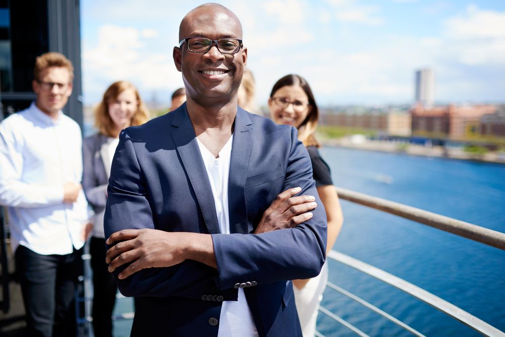 Proud businessman with arms crossed in front of his colleagues