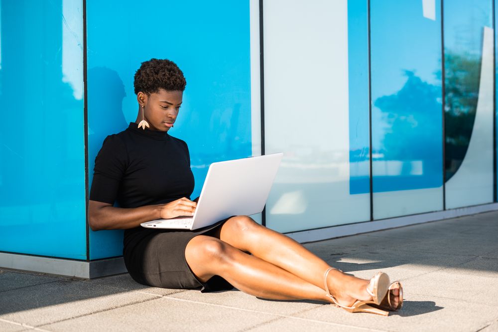 Serious female surfing laptop near modern building