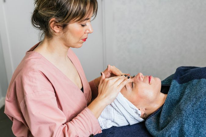 Smiling masseuse doing massage for woman in spa salon