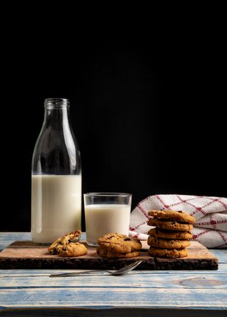 Milk and fresh cookies on board near napkin