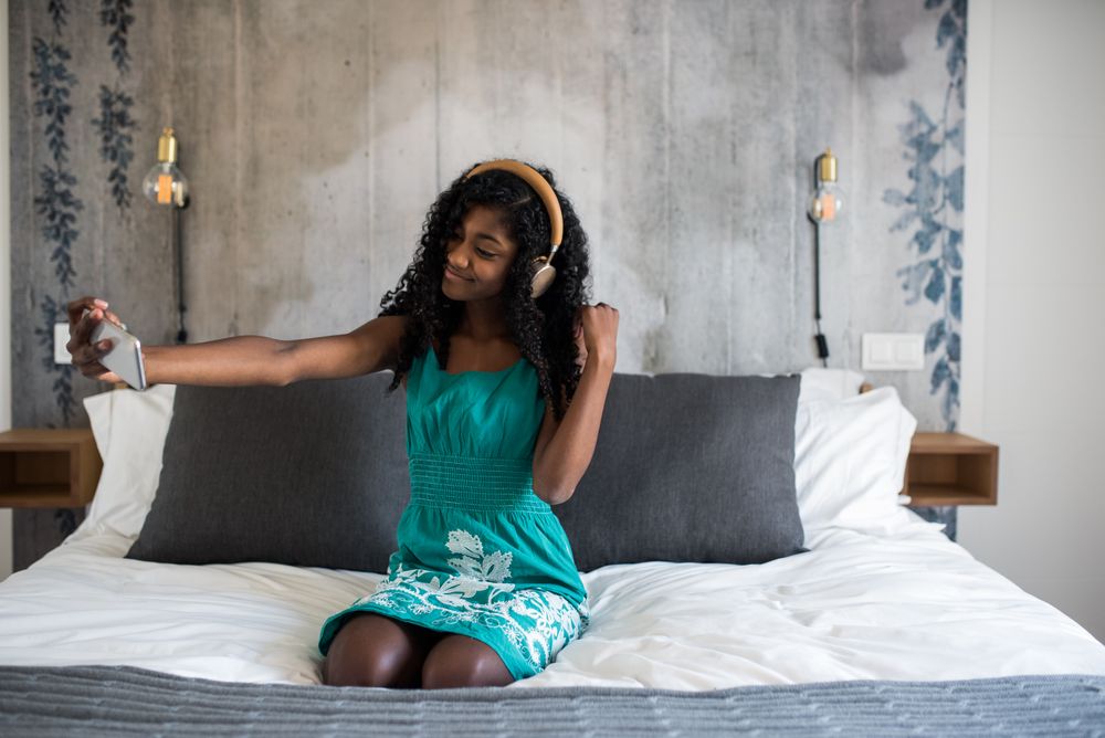 Black girl with on bed taking a selfie