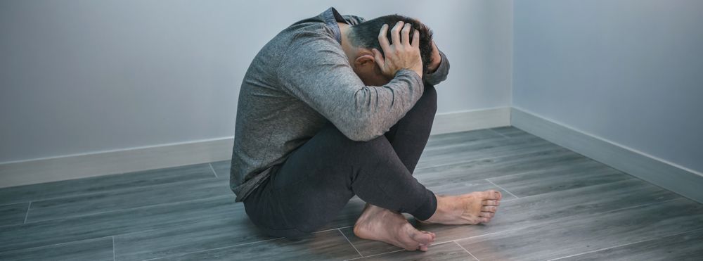 Unrecognizable man with problems sitting on the floor
