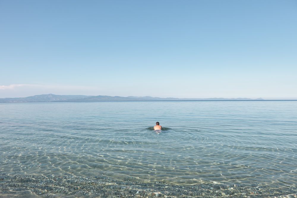 Man swimming in clear water in sunlight