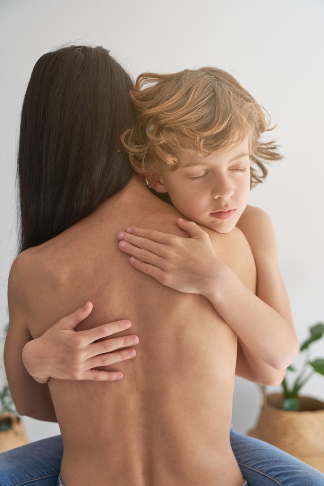 Boy hugging unrecognizable topples mother