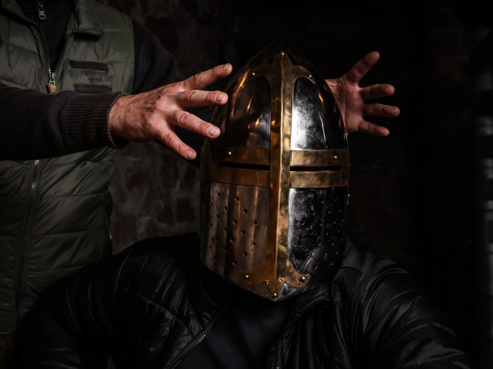 A man in a medieval iron knight's helmet.
