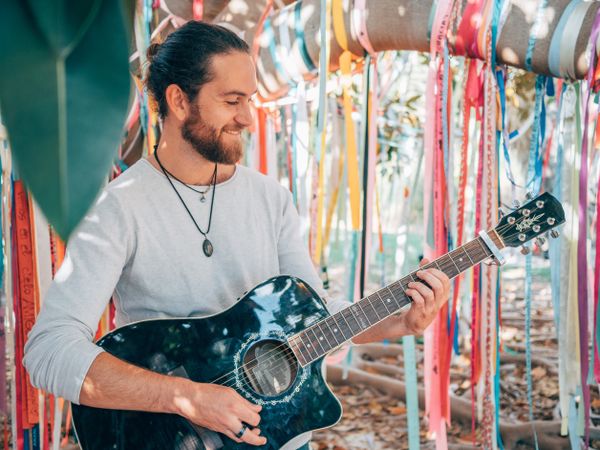 Man playing guitar under decorated tree