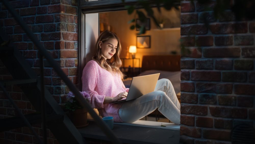 Creative Female in Comfy Clothes Smiles and Writes her Diary in her Electronic Journal