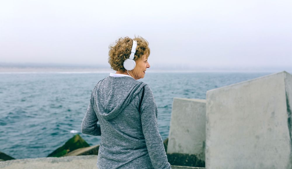 Mature sportswoman with headphones looking aside