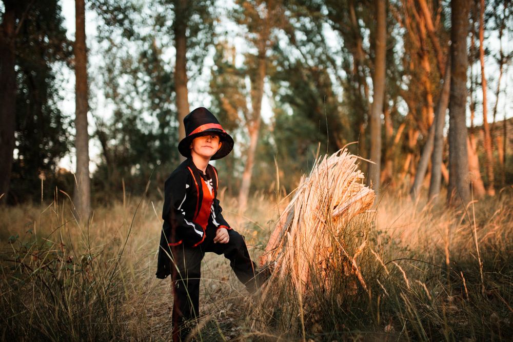 Boy in halloween costume with leg up on wood in the forest