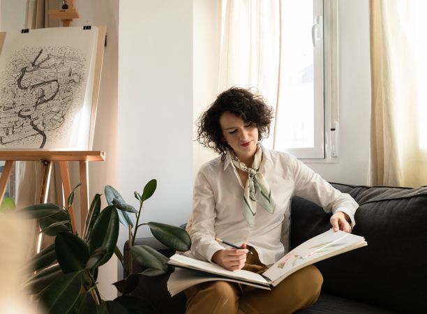 Woman writing on paper on sofa in room